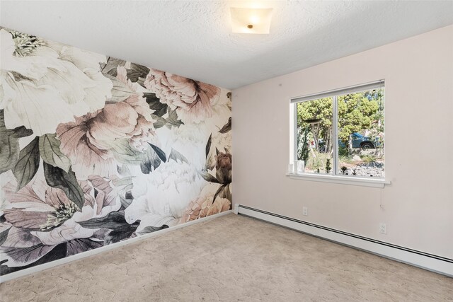 spare room with a baseboard heating unit, carpet, and a textured ceiling