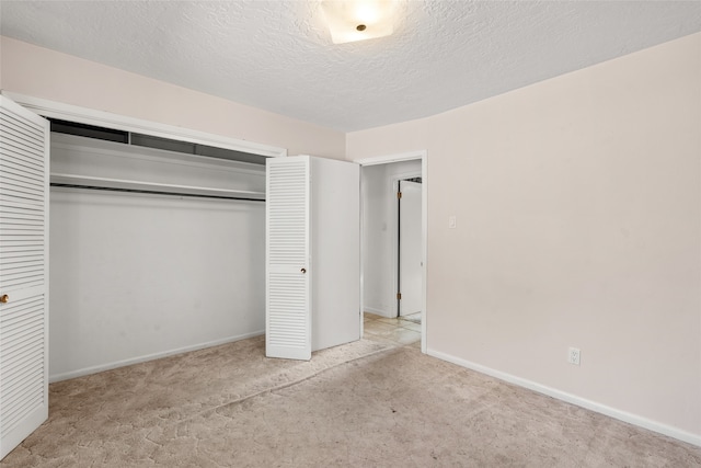 unfurnished bedroom featuring light carpet, a closet, and a textured ceiling