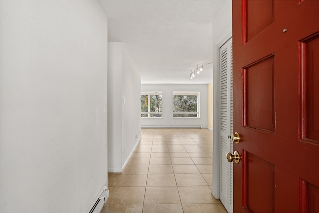 hallway featuring a textured ceiling, baseboard heating, and light tile patterned floors