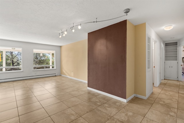 tiled empty room with a textured ceiling and a baseboard radiator