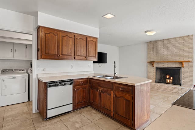 kitchen with kitchen peninsula, sink, white dishwasher, and a brick fireplace