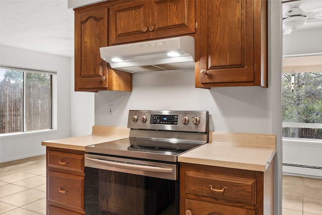 kitchen featuring light tile patterned floors, stainless steel electric range oven, and a wealth of natural light