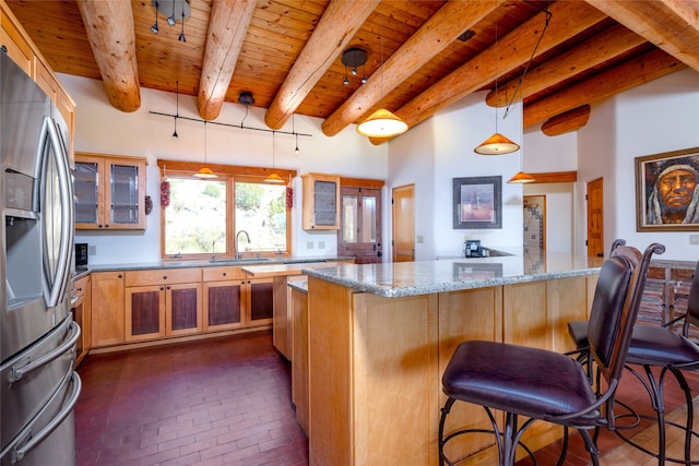 kitchen featuring light stone countertops, a kitchen bar, beam ceiling, decorative light fixtures, and stainless steel fridge with ice dispenser