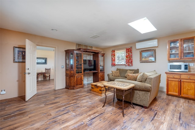 living room featuring an AC wall unit, wood-type flooring, and a skylight