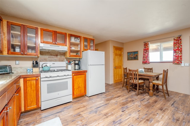 kitchen featuring light wood-type flooring, white appliances, and backsplash