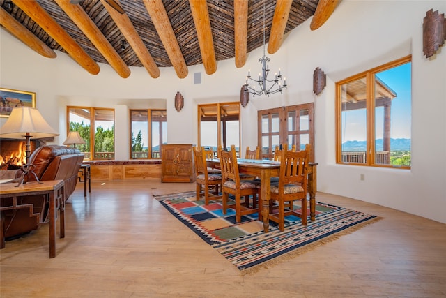 dining room featuring an inviting chandelier, a towering ceiling, hardwood / wood-style floors, and beam ceiling