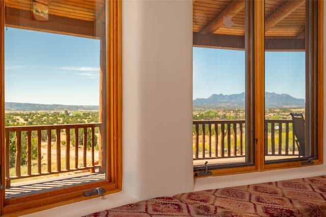 unfurnished bedroom with a mountain view, beamed ceiling, and wooden ceiling