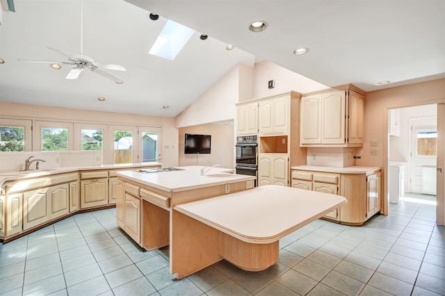 kitchen featuring light tile patterned floors, ceiling fan, a skylight, and a kitchen island