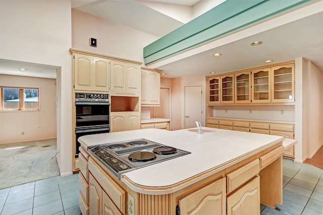 kitchen with a center island with sink, stainless steel cooktop, light tile patterned floors, and sink