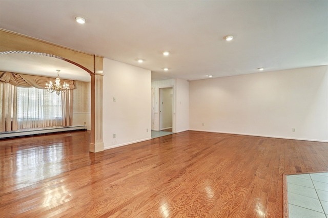 spare room with a notable chandelier, light hardwood / wood-style floors, and a baseboard heating unit