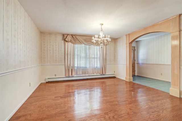 unfurnished room with a baseboard radiator, hardwood / wood-style flooring, and an inviting chandelier