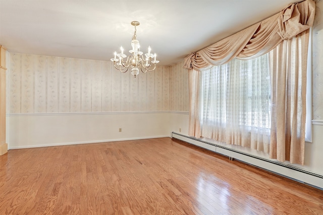 empty room featuring a baseboard heating unit, wood-type flooring, and a notable chandelier