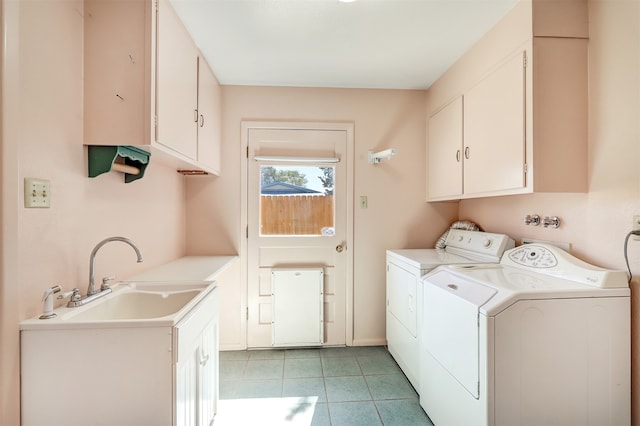 clothes washing area featuring separate washer and dryer, sink, light tile patterned floors, and cabinets