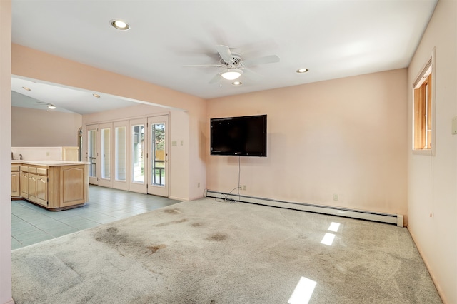 unfurnished living room with light carpet, ceiling fan, baseboard heating, and sink