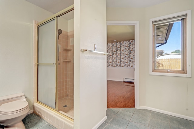 bathroom featuring tile patterned floors, baseboard heating, a shower with shower door, and toilet