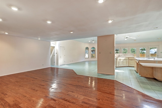 unfurnished living room featuring ceiling fan, light wood-type flooring, and sink