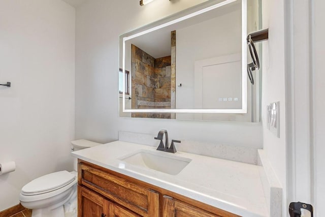 bathroom with a tile shower, vanity, and toilet