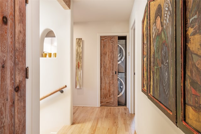 hall with stacked washer and dryer and light hardwood / wood-style flooring