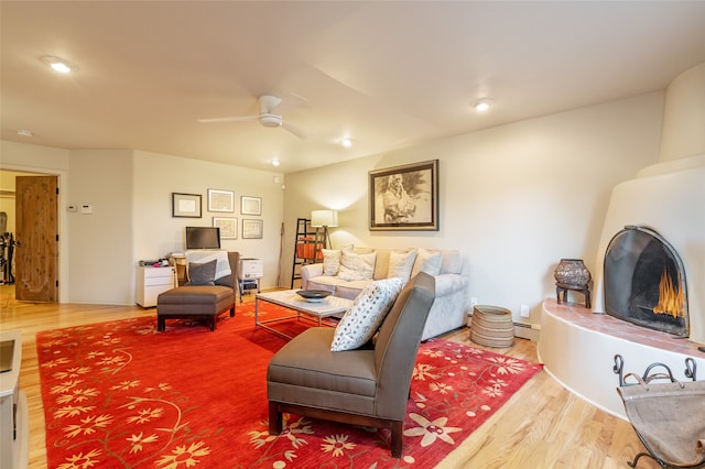 living room featuring hardwood / wood-style flooring, baseboard heating, and ceiling fan