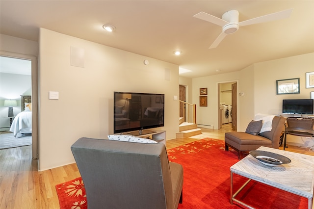 living room with hardwood / wood-style flooring, washer and clothes dryer, a baseboard heating unit, and ceiling fan