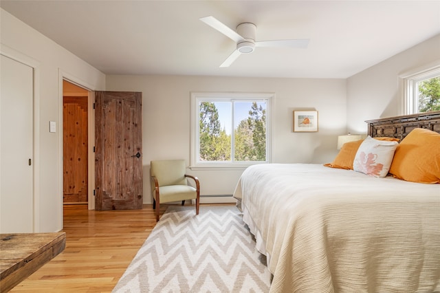 bedroom with baseboard heating, ceiling fan, and light hardwood / wood-style flooring