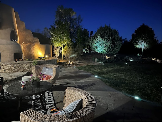 patio at twilight featuring an outdoor stone fireplace