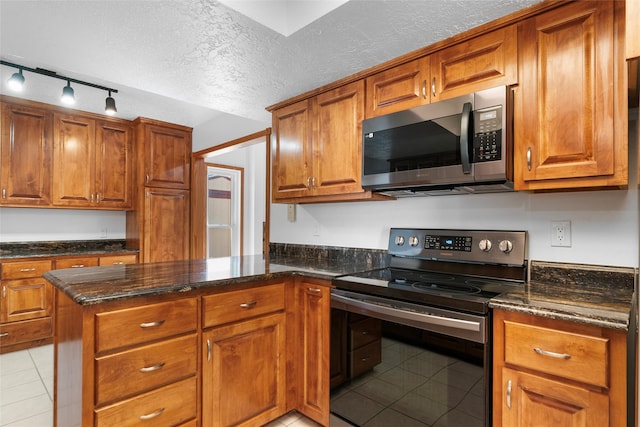 kitchen featuring rail lighting, black / electric stove, dark stone countertops, light tile patterned floors, and a textured ceiling