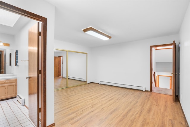 unfurnished bedroom with a baseboard radiator, light hardwood / wood-style flooring, and a closet