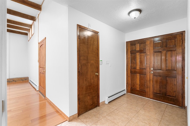 tiled entrance foyer featuring a baseboard radiator and a textured ceiling