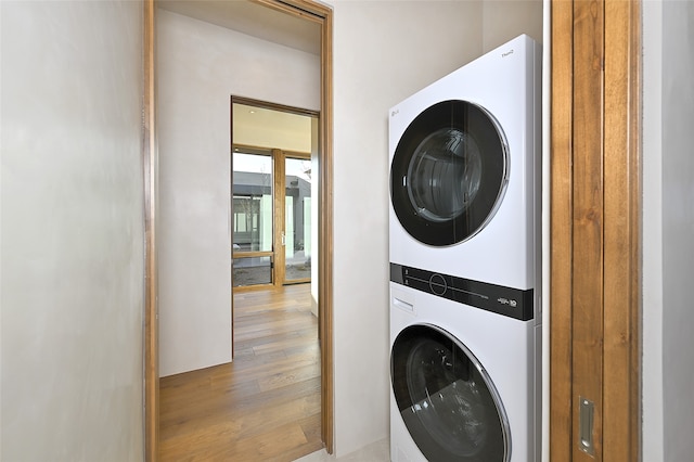 clothes washing area featuring light wood-type flooring and stacked washing maching and dryer