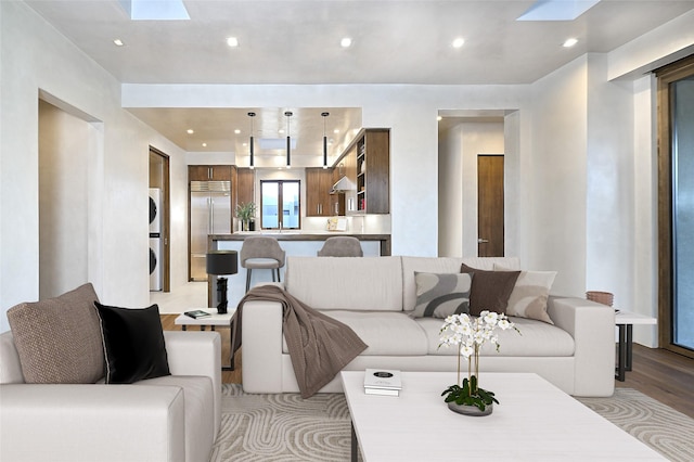 living room with stacked washer / dryer, a skylight, and light hardwood / wood-style floors