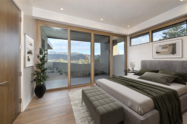 bedroom featuring access to outside, multiple windows, a mountain view, and light hardwood / wood-style floors