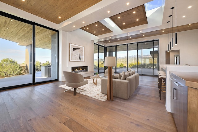 living room with light hardwood / wood-style floors, a wall of windows, and wood ceiling