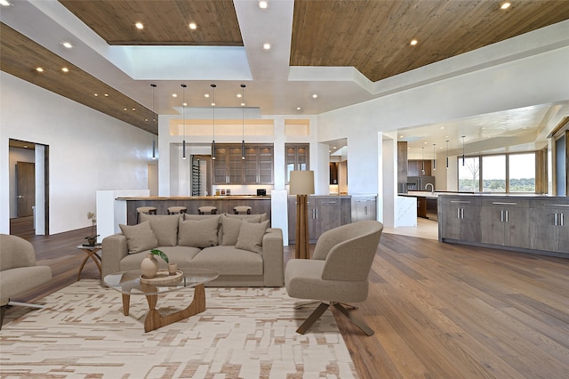 living room with a towering ceiling, light hardwood / wood-style flooring, and wood ceiling