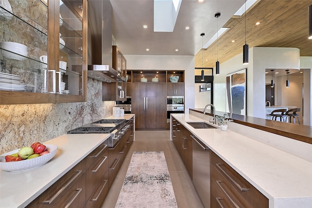 kitchen featuring sink, tasteful backsplash, decorative light fixtures, wall chimney exhaust hood, and appliances with stainless steel finishes