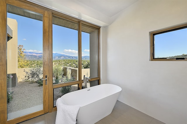 bathroom featuring a mountain view, plenty of natural light, and a bath