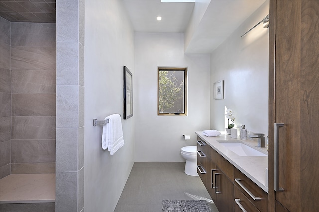 bathroom with vanity, toilet, and tiled shower