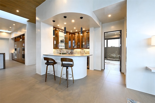 kitchen featuring a breakfast bar area, hanging light fixtures, kitchen peninsula, and decorative backsplash