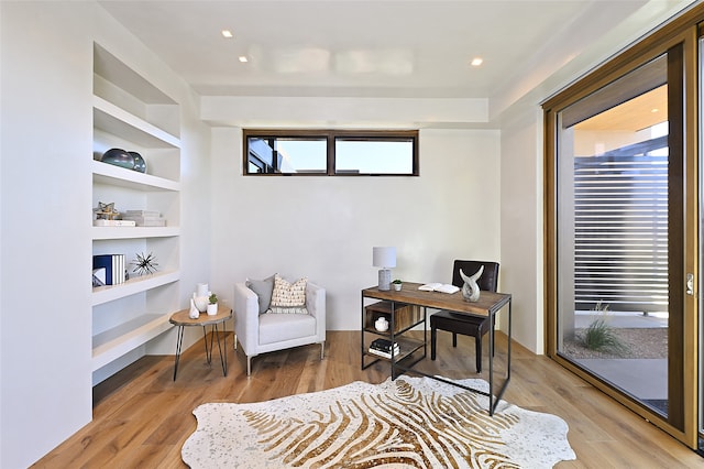 office space featuring built in shelves, plenty of natural light, and light hardwood / wood-style floors