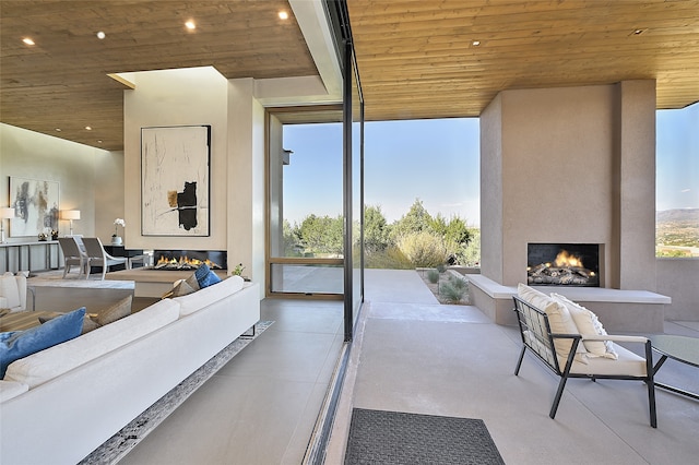 living room with expansive windows, a fireplace, and wood ceiling