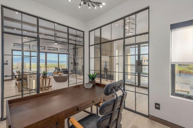 office space with french doors, ceiling fan with notable chandelier, and light hardwood / wood-style floors