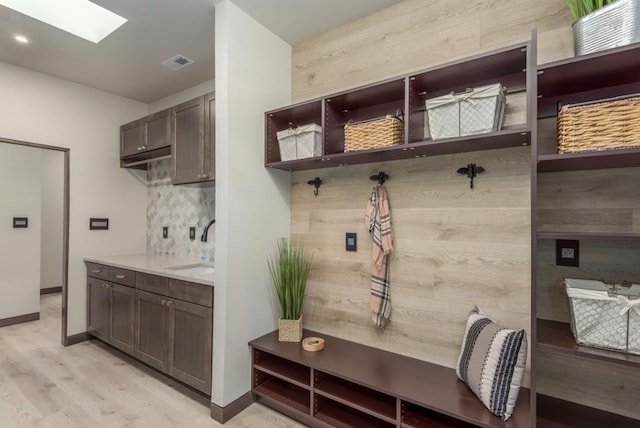 mudroom with light hardwood / wood-style floors, a skylight, and sink