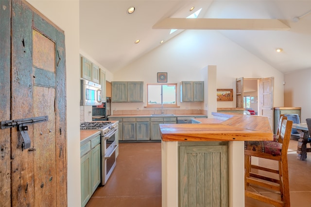 kitchen featuring beam ceiling, kitchen peninsula, appliances with stainless steel finishes, and green cabinetry