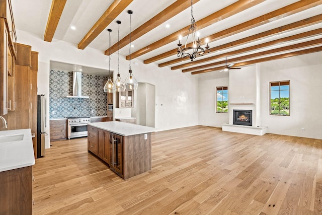 kitchen with pendant lighting, sink, beam ceiling, high end stainless steel range oven, and a kitchen island