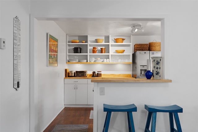 bar with stainless steel fridge, white cabinetry, dark hardwood / wood-style floors, and wood counters