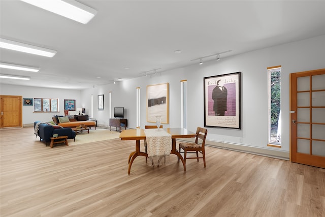 dining space with rail lighting and light hardwood / wood-style floors