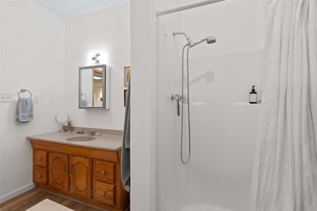 bathroom with walk in shower, vanity, and hardwood / wood-style flooring