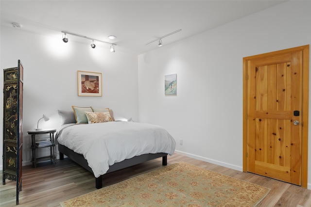 bedroom featuring track lighting and hardwood / wood-style floors