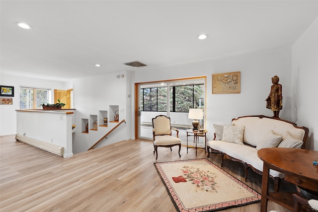 living room with light hardwood / wood-style floors, a baseboard radiator, and plenty of natural light