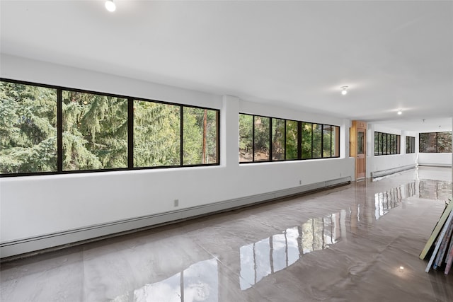 empty room featuring baseboard heating and plenty of natural light